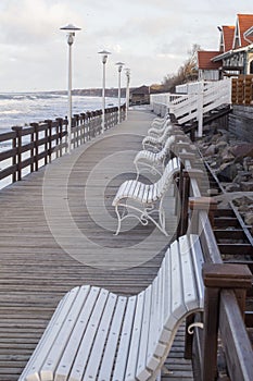 View across and empty deserted row of benches at the end of the pier looking towards the promenade