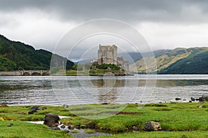View from across a grassy shoreline to the Eilean Donan Castle and bridge