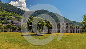 A view across a park towards the remains of the Roman amphitheater in front of the city of Gubbio, Italy