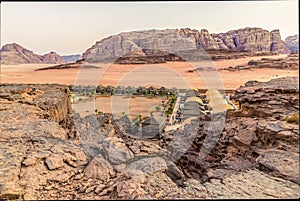 A view across the rocky terain over a campsite in the desert landscape in Wadi Rum, Jordan at sunset