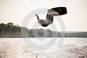 view on active male wakeboarder doing somersault in the air above water