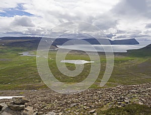 View on adalvik and latrar in west fjords nature reserve Hornstrandir in Iceland with lake and river stream, green grass photo