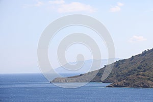 View of the Aegean Sea, mountains and rocks from the high shore near Marmaris, white sail and sailboat, Turkey, May 19