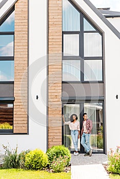 View of african american man and woman standing outside near house