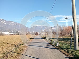 view of agricultural fields with mountains on a sunny day in northern Italy with road. Rural scene