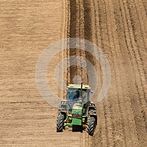 View of agricultural landscape, tractor plowing dry farmland in daytime