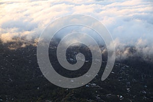 view from the air of an airplane above the clouds and green trees