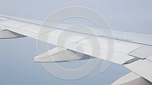view through aircraft window with plane\'s wing over blue sky