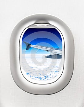 View of aircraft wing and clouds from airplane window