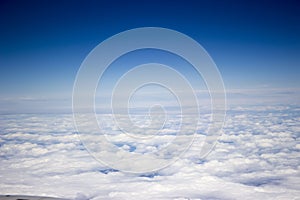 A view from the airplane, above white endless clouds, blue sky