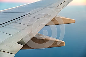 View from airplane on the aircraft white wing flying over ocean landscape in sunny morning. Air travel and transportation concept