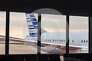 View of airplane fuselage tail through window at airport