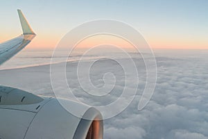 The view from the airplane`s illuminator to the wing, airplane turbine and fluffy clouds at sunrise. Flying over the