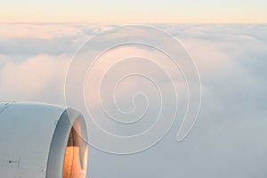 The view from the airplane`s illuminator to the wing, airplane turbine and fluffy clouds at sunrise. Flying over the