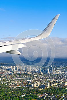 View of airplane white wing flying in blue sky over clouds.