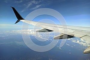 View through airplane window of commercial jet plane wing flying high in the sky. Air travelling concept