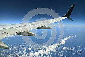 View through airplane window of commercial jet plane wing flying high in the sky. Air travelling concept