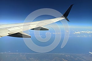 View through airplane window of commercial jet plane wing flying high in the sky. Air travelling concept