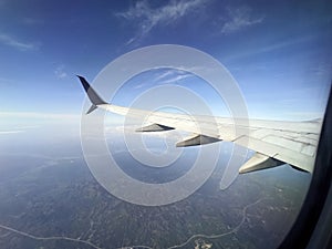 View through airplane window of commercial jet plane wing flying high in the sky. Air travelling concept