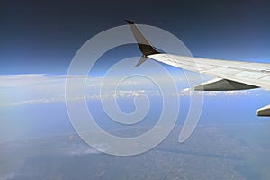 View through airplane window of commercial jet plane wing flying high in the sky. Air travelling concept