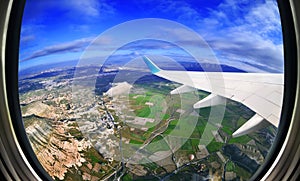 View from airplane window on fields and mountains