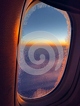 View from airplane window at orange and purple sunset. Golden hour. Travel and relax concept