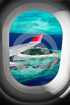 View through airplane window on plane flight wing in front of tropical island indian ocean maldive. transportation vacation air