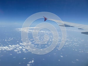 View from airplane window on plane wing and sky with clouds