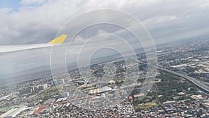 View from the airplane window showing skyline, clouds, beautiful forest, ocean, ships, mountains, islands, houses and buildings