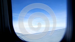 View from the airplane window. The sky, clouds, wing of an airplane can be seen. The weather is clear, it is a sunny day