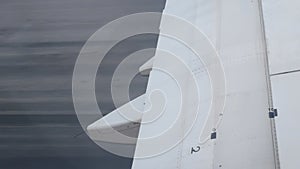 view through airplane window to the wing while aircraft running for take off from runway in international airport ready to travel