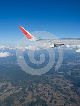 View from airplane windows from passenger, beautiful cloud group, blue sky and landscape. Wing aircraft in altitude during flight.