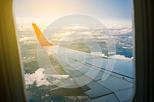 View of an airplane wing from the window on the city. Flight on a passenger plane. Clouds and sky outside the airliner window.