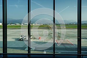 View through the airport departure terminal window to the runway