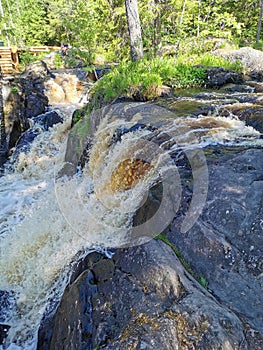 View of the Akhvenkoski waterfall on the Tokhmayoki River in Karelia from the pedestrian bridge passing over it photo