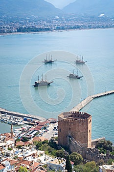 View of Alanya harbour, ships and Kizil Kule Red Tower, ancient stone wall of Alanya Castle. Alanya, Turkey