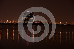 View of Aldar headquarters building and night skyline of Abu Dhabi