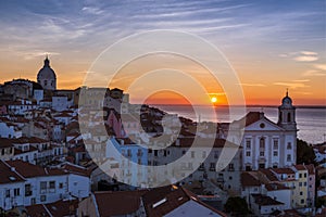 View of the Alfama neighborhood from the Portas do Sol viewpoint at sunrise in Lisbon, Portugal