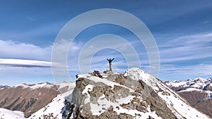 View from all sides, of a happy man with raised hands as a symbol of victory, looking at a panoramic view of the snow