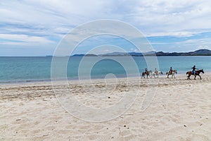 A view along the beach towards horse riders at Tamarindo