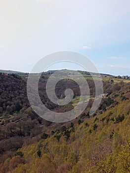 View along the colden valley in calderdale near hebden bridge with the village of colden on the hills above the woodland