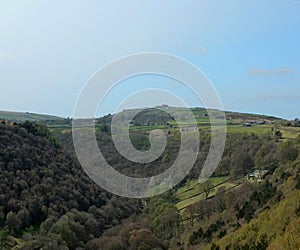 View along the colden valley in calderdale near hebden bridge with the village of colden on the hills above the woodland