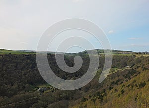 View along the colden valley in calderdale near hebden bridge with the village of colden on the hills above the woodland