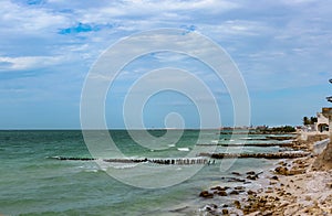 View along eroded beach with sand fencing in Progreso Mexico toward the worlds longest pier that allows ships to dock in the shall