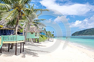 View along Lalomanu Beach, Upolu Island, Samoa, of colorful Samoan beach fale huts that are an alternative to hotel or resort