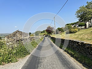 View along, Marridales Road, with dry stone walls, and houses in, Gayle, Hawes, UK