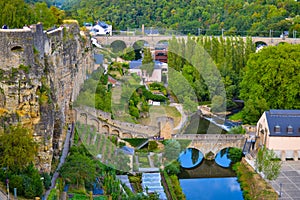 View of Alzette river crossing the old town of Luxembourg City, Luxembourg, with a bridge and houses in one side and the wall in