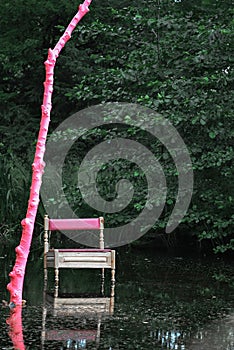 View of an ancient chair in the water with a pink-painted tree