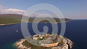 View of the ancient fortress Mamula, a yacht near it and the coast of the bay