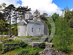 View of an ancient gray brick church framed by green vegetation in Cetinje, the capital of Montenegro
